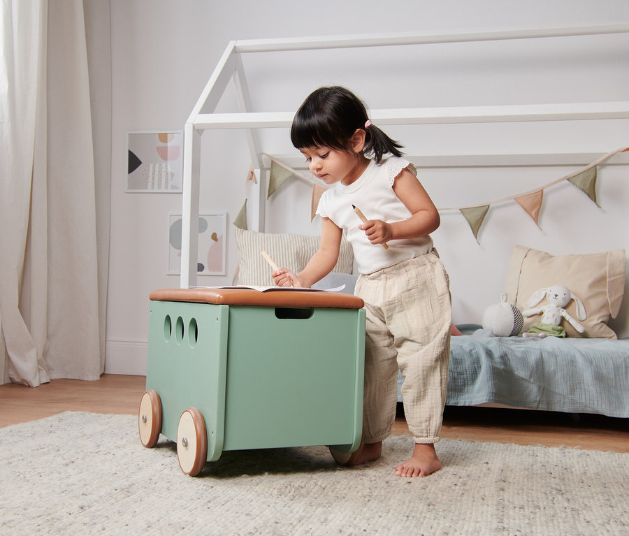 Ein Mädchen zeichnet am Tisch und trägt eine beige Schlupfwebhose aus Bio-Baumwolle.