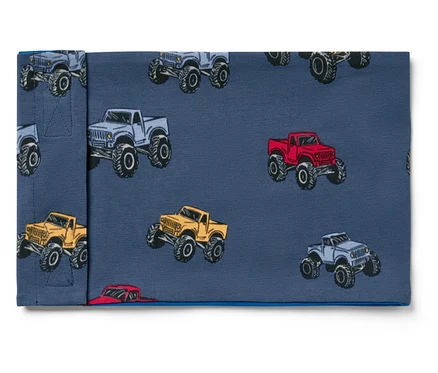 Stoff mit Monstertruck-Muster in Grau, Rot und Gelb auf blauem Hintergrund.