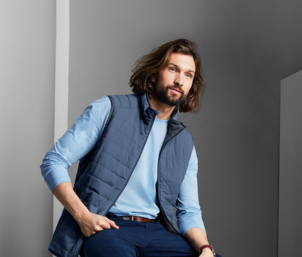 Mann sitzt auf Hocker mit Wende-Steppweste.