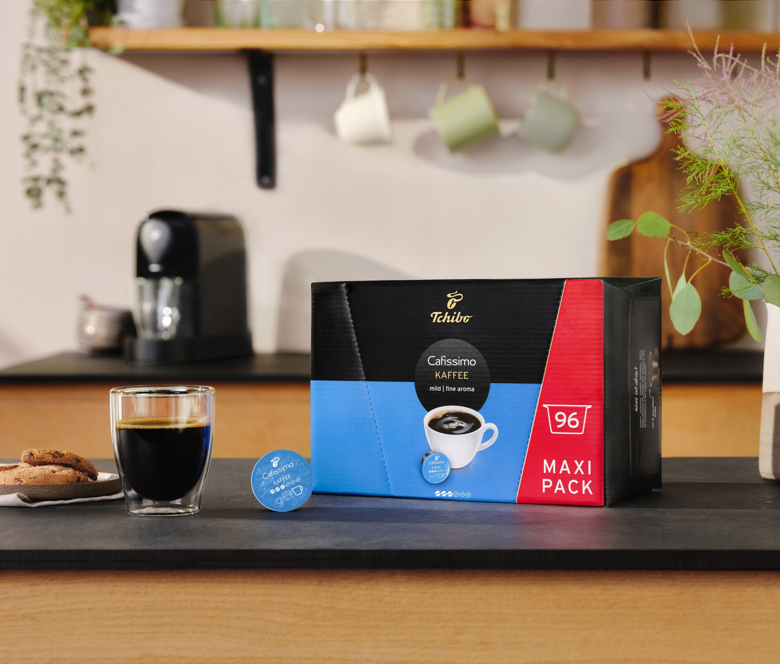 Ein Glas Kaffee und Kekse neben einer Packung Cafissimo Kaffee kräftig - 30 Kapseln.