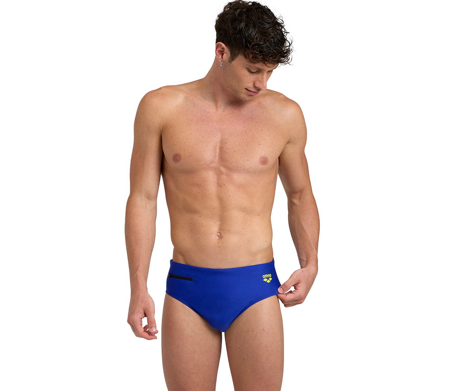 Mann trägt eine blaue arena Badehose Slip Zip mit Reißverschluss, blickt nach unten und hält den Bund.