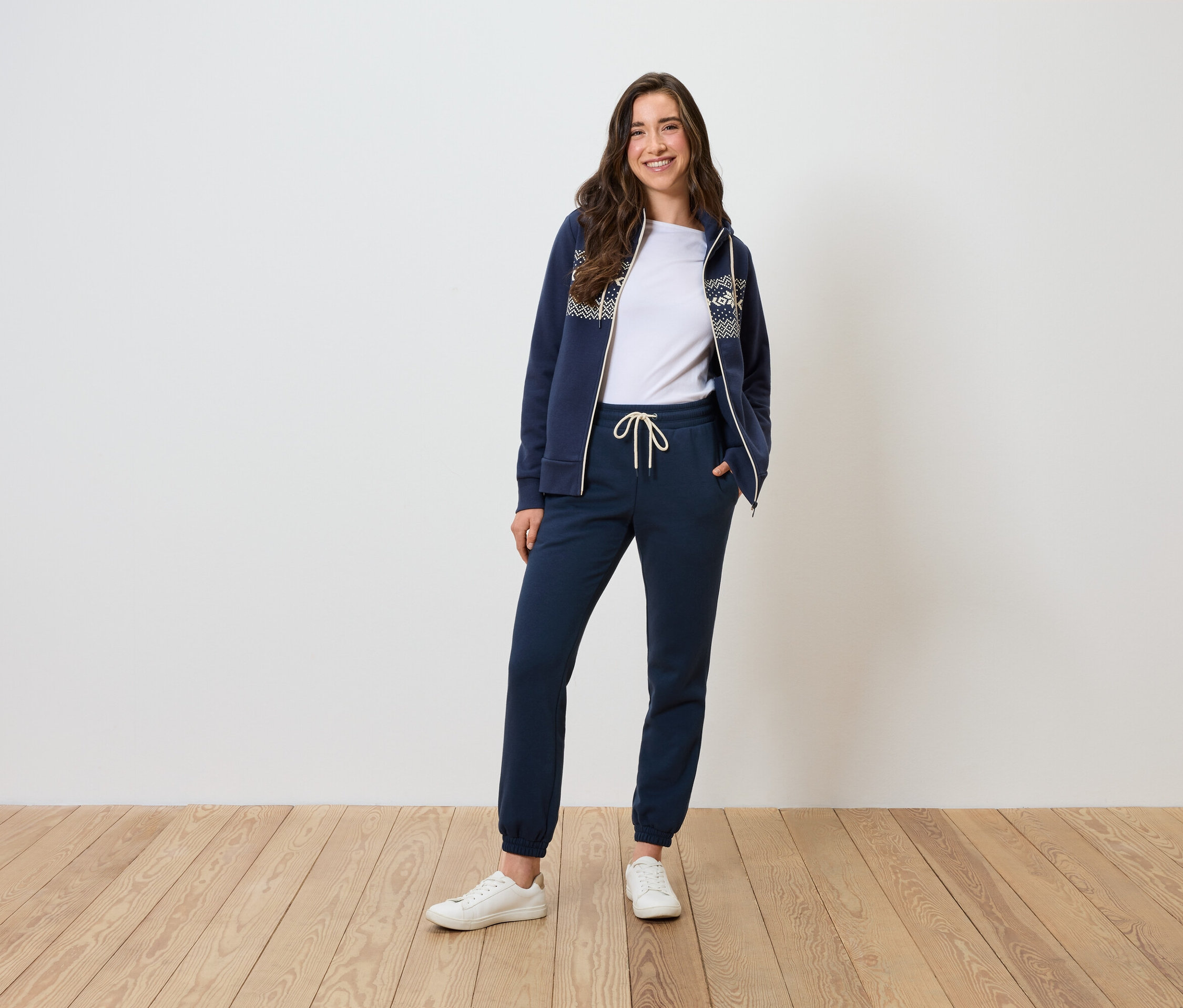 Frau posiert in marineblauem Trainingsanzug und weißem T-Shirt.