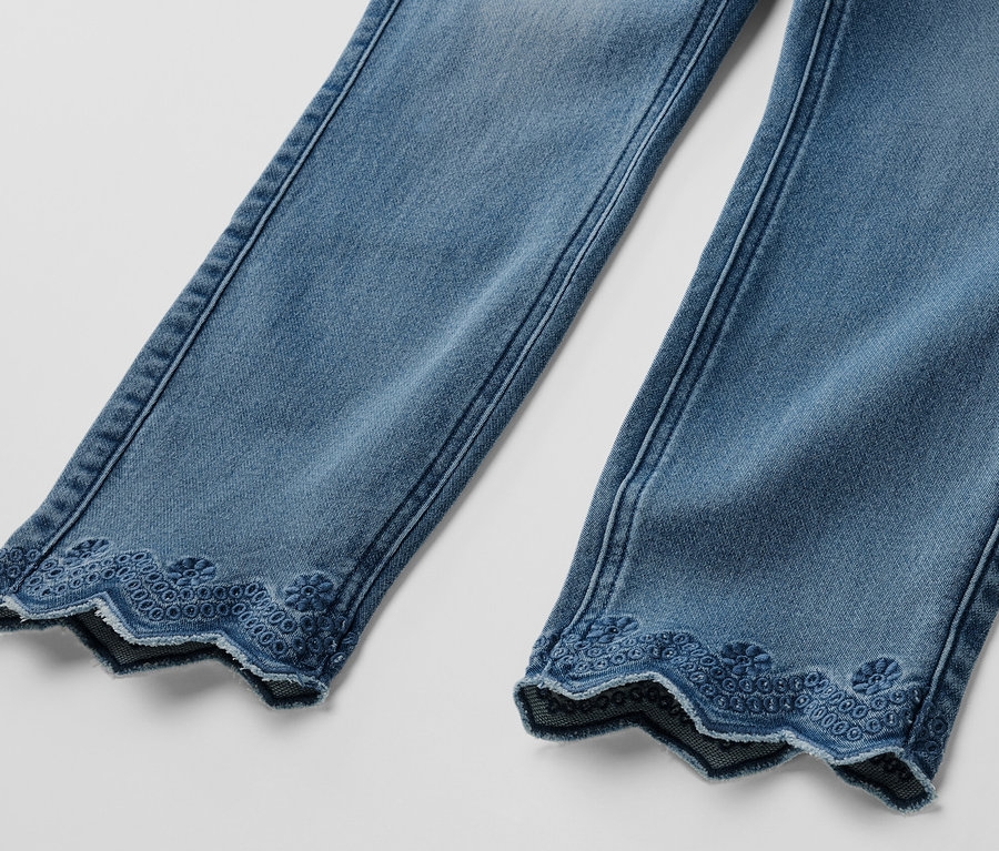 Detailansicht von zwei Beinen einer hellblauen 7/8-Treggings mit Lochstickerei am Saum.