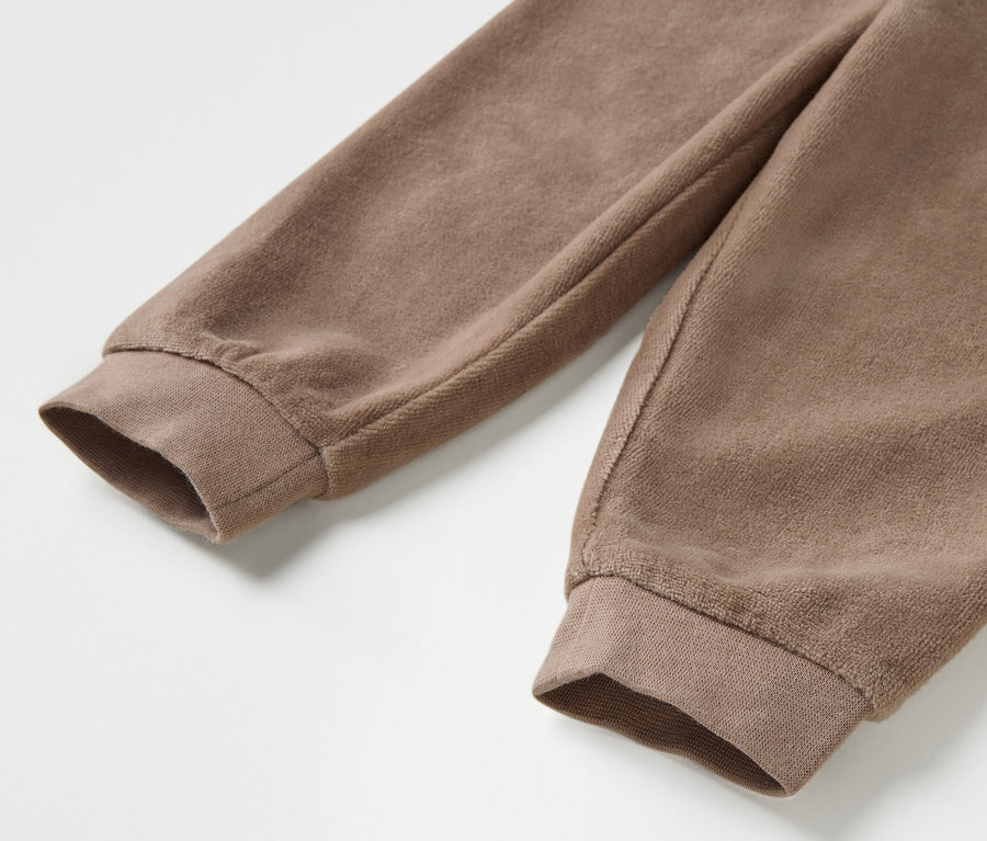 Detailaufnahme eines braunen Baby-Nicki-Sets mit langen Ärmeln.