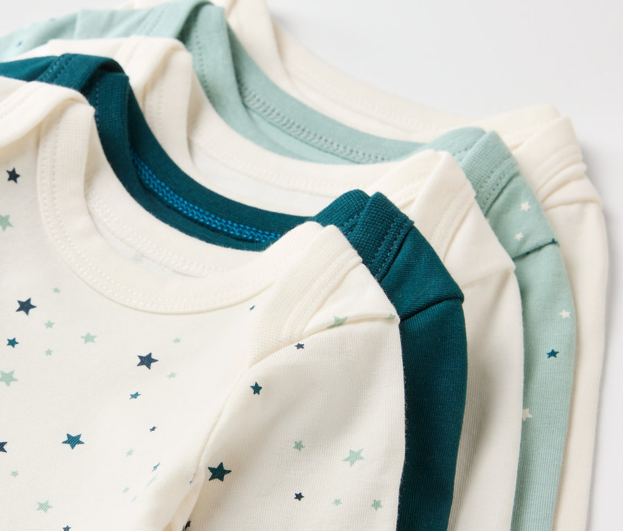 Detailansicht von drei Babybodys mit Sternen in den Farben Weiß, Dunkelgrün und Hellgrün.