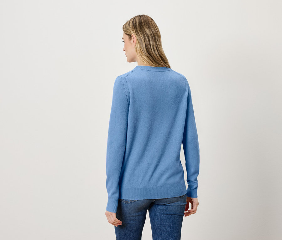 Rückansicht einer blonden Frau mit blauem Pullover und Jeans.