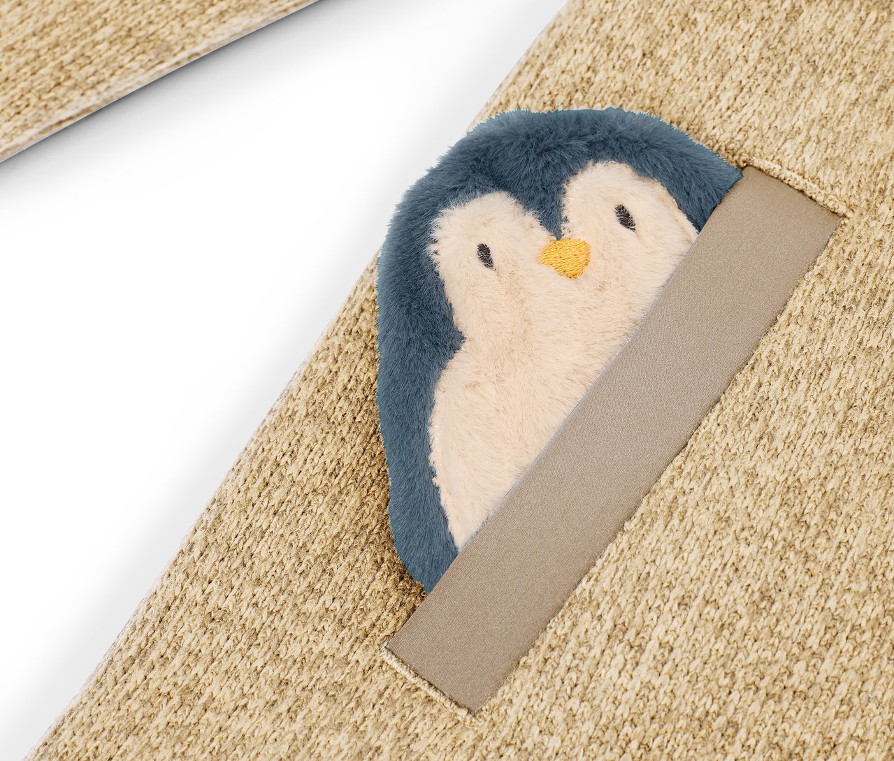 Detail eines beigen Teppichs mit aufgenähtem Plüschpinguin.