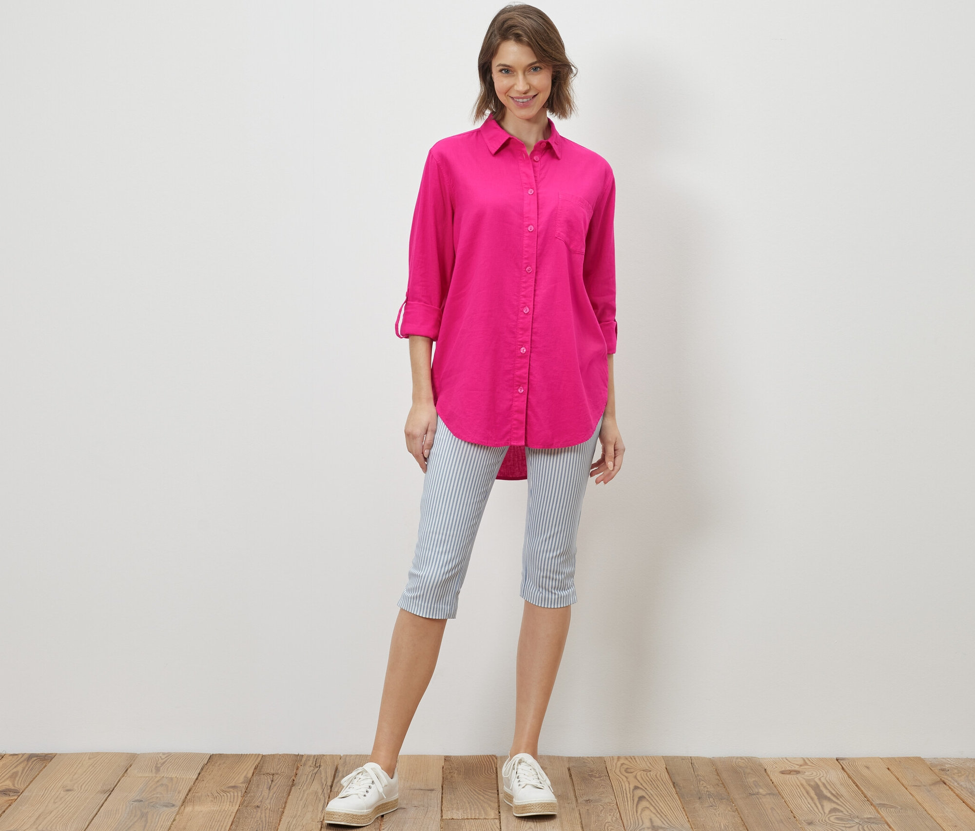 Frau steht und trägt eine lange Leinenbluse, pink.