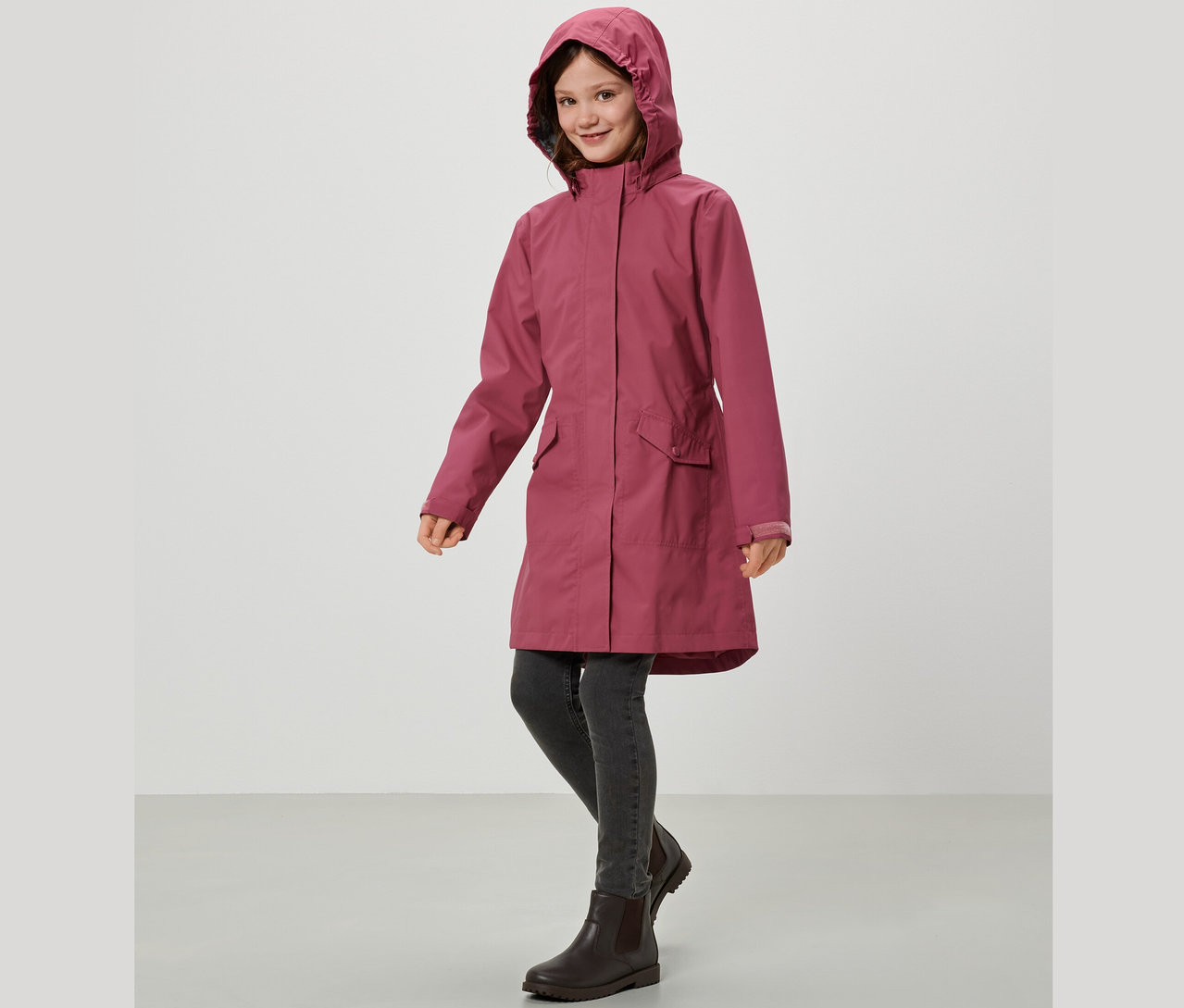 Lächelndes Mädchen trägt einen Kinder-Regenparka.