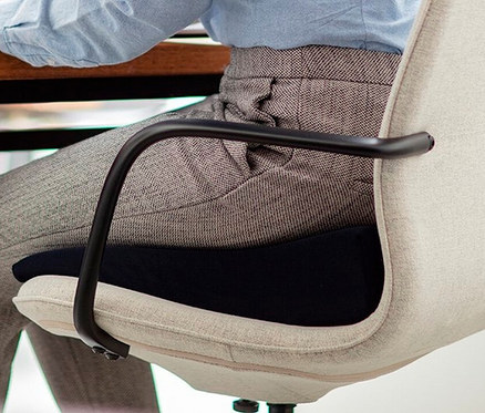 Eine Person sitzt auf einem Stuhl mit einem TEMPUR® Keilsitzkissen.