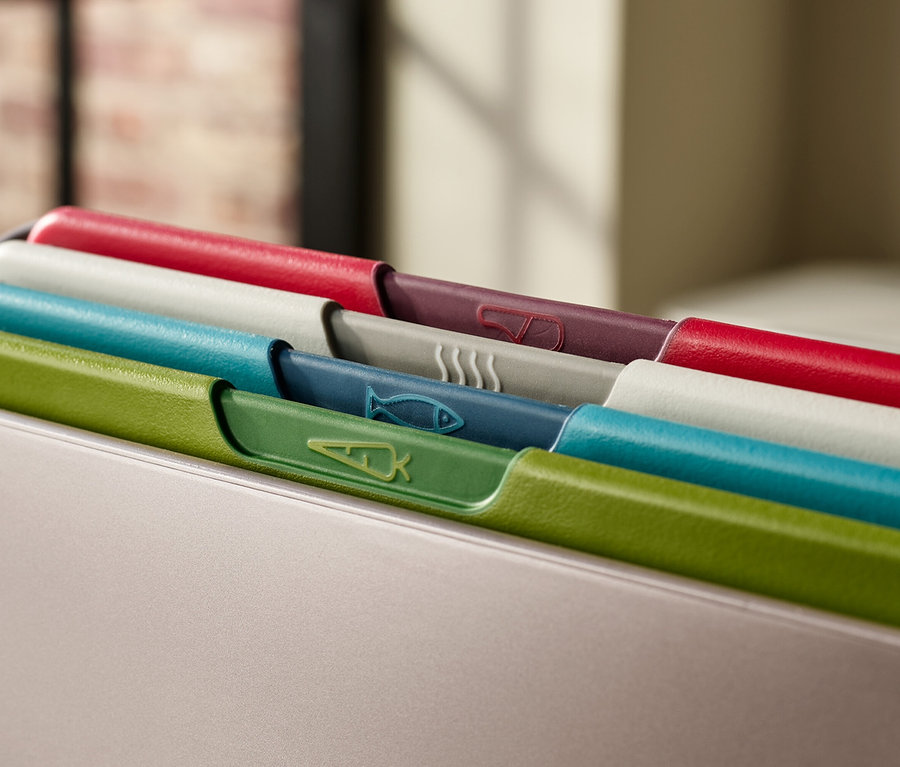 Mehrfarbige Schneidebretter mit Symbolen in einem Behälter.