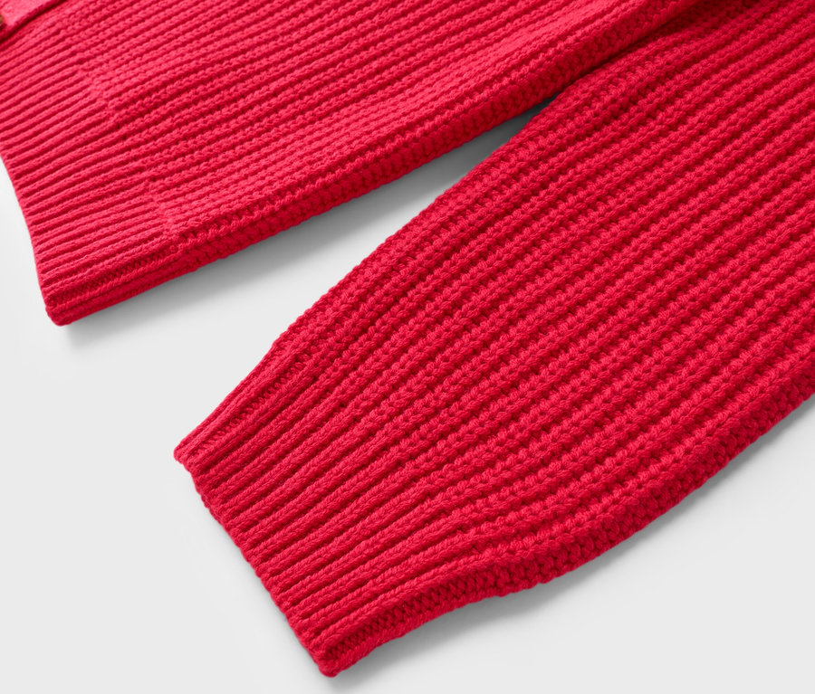 Detailansicht eines roten Strickcardigans mit goldenen Knöpfen auf hellem Hintergrund.