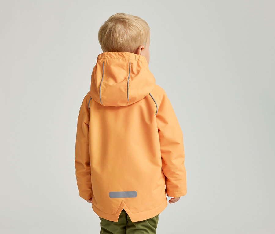 Rückansicht eines Kindes mit blonden Haaren in einer orangefarbenen Jacke mit Kapuze und grüner Hose vor einem hellen Hintergrund.