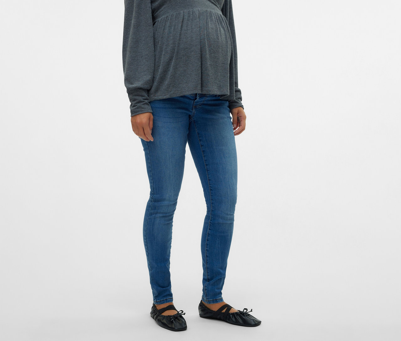 Schwangere trägt graues Oberteil und MAMALICIOUS Skinnyjeans »MLMILA« mit flachen, schwarzen Schuhen.