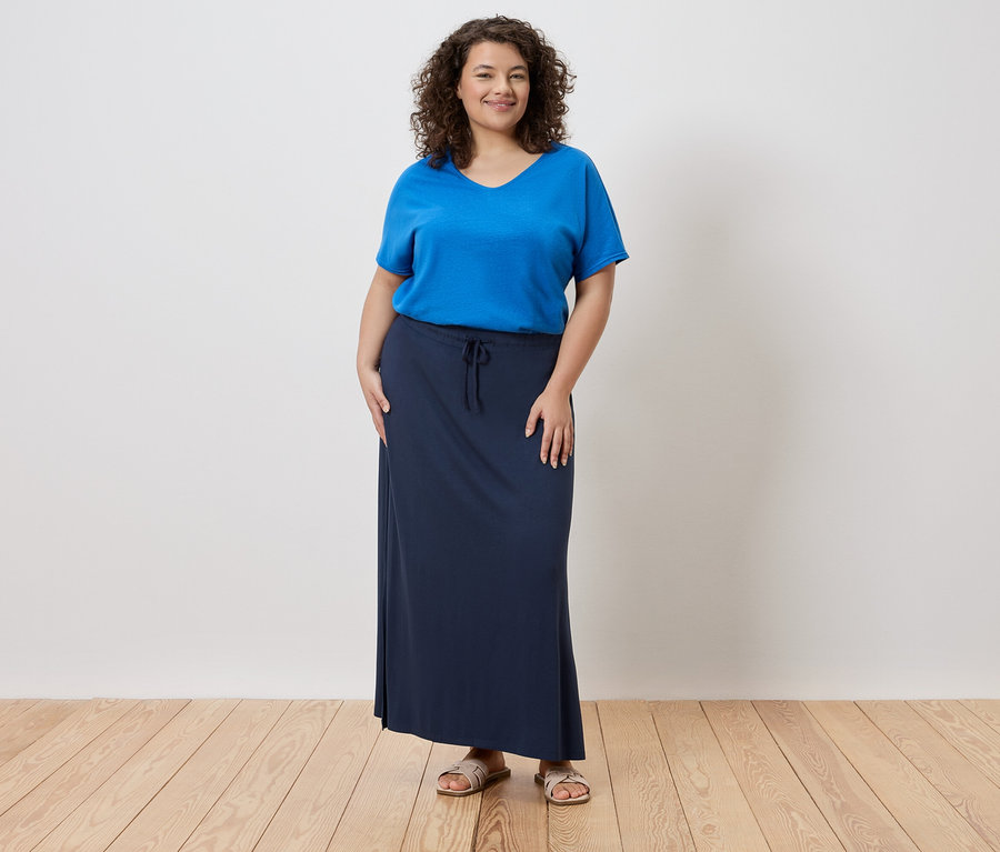 Frau trägt ein blaues T-Shirt und einen langen, marineblauen Rock.