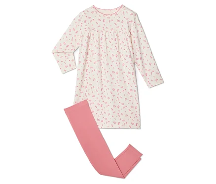Ein weißes Nachthemd mit rosa Blumenmuster liegt neben einer rosa Leggings.