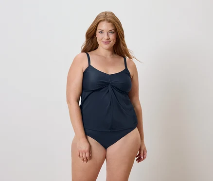 Frau mit langen roten Haaren, die einen marineblauen Badeanzug trägt.