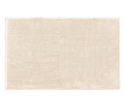 Ein quadratischer, beiger Teppich liegt flach auf dem Boden.