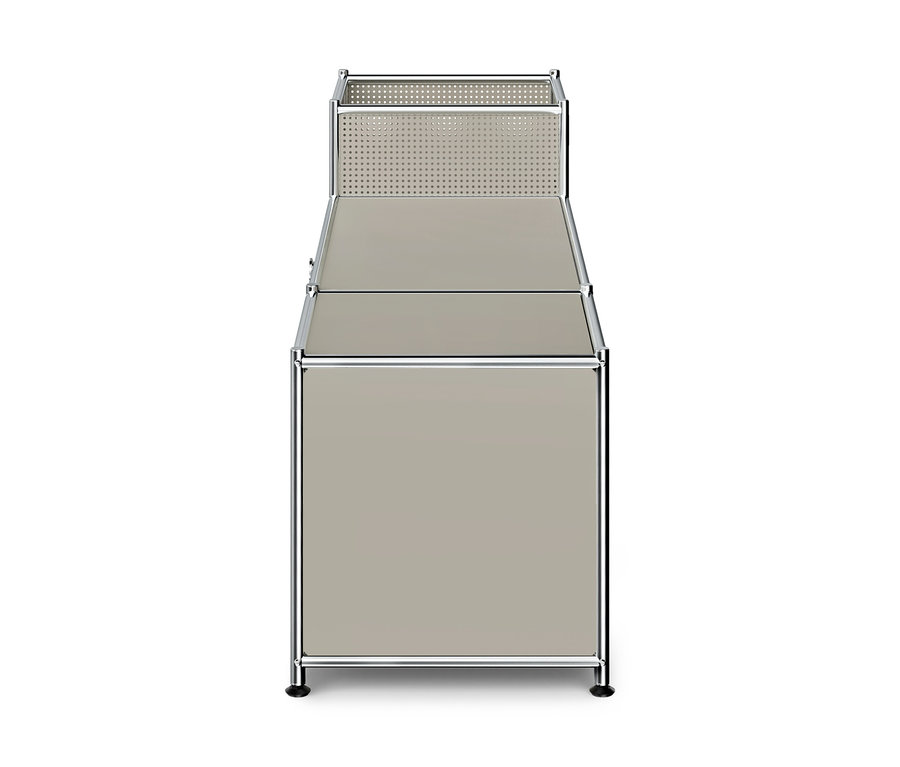 Modulares Aufbewahrungsmöbel mit Chromrahmen und beigefarbenen/grauen Paneelen. Der obere Bereich ist ein offener, perforierter Korb. Darunter befindet sich eine flache Oberfläche und der untere Bereich ist ein geschlossener Schrank.