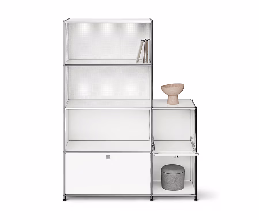 Weißes modulares Regal mit Chromrahmen und mehreren Fächern. Links drei offene Regalebenen mit Büchern oben und ein geschlossener Schrank unten. Rechts ein offenes Fach mit einer Holzschale und ein Fach mit geöffneter Klapptür, in dem ein grauer Hocker steht.