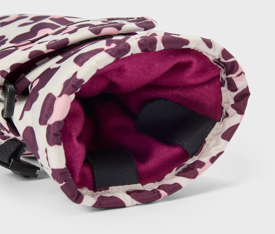 Nahaufnahme eines Handschuhs mit Leopardenmuster in Weiß, Pink und Lila, der sein dunkelpinkes Fleecefutter und einen schwarzen Riemen an der Seite zeigt.