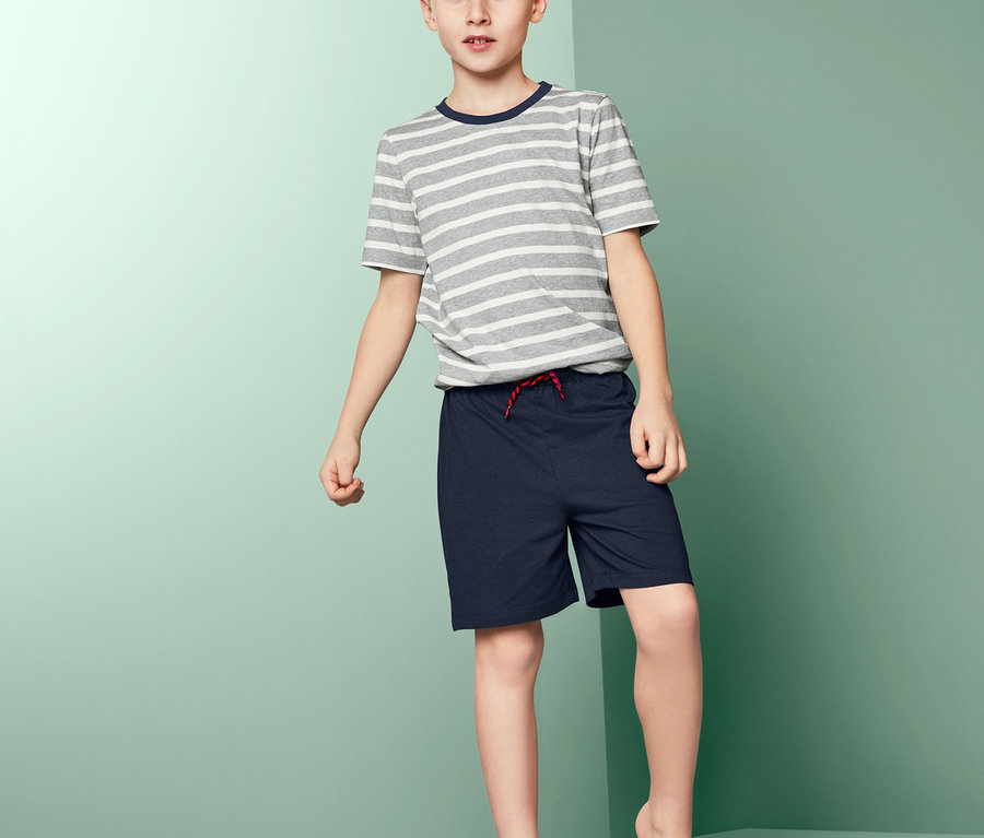 Junge steht auf einer Plattform und trägt einen Jungen-Shorty-Pyjama.