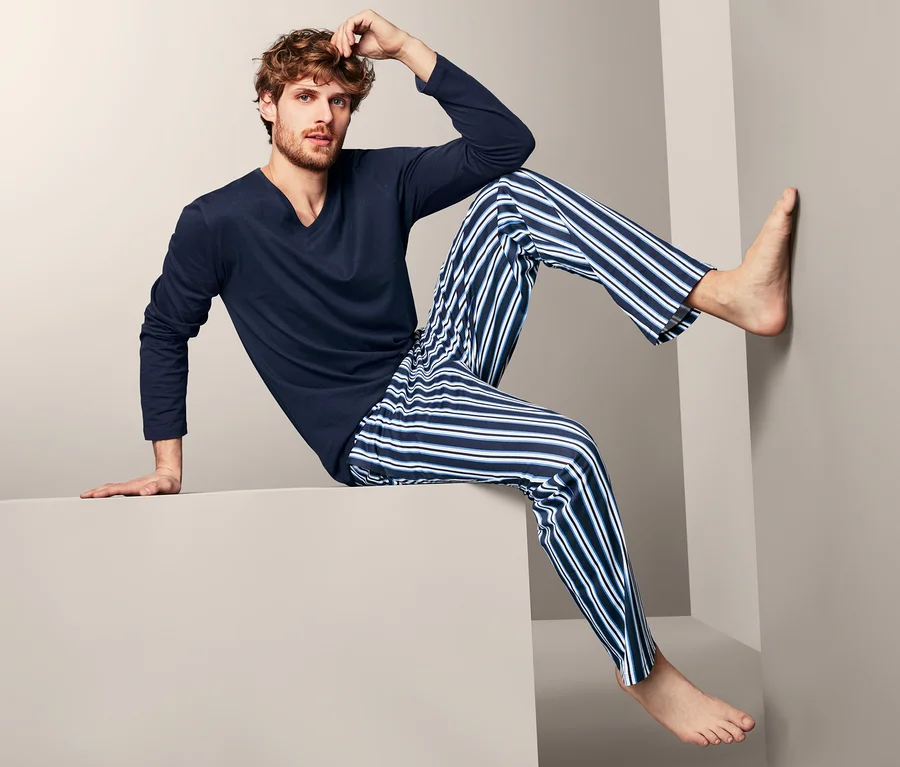 Mann sitzt in einem Pyjama auf einem Würfel.