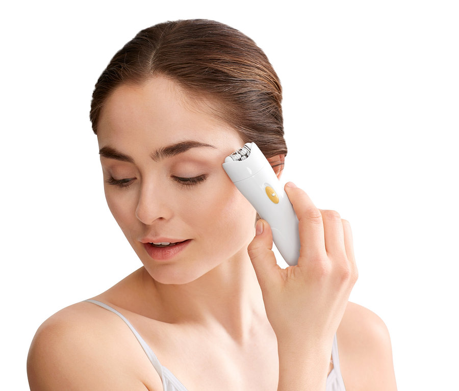 Frau epiliert ihr Gesicht mit einem Epilierer.