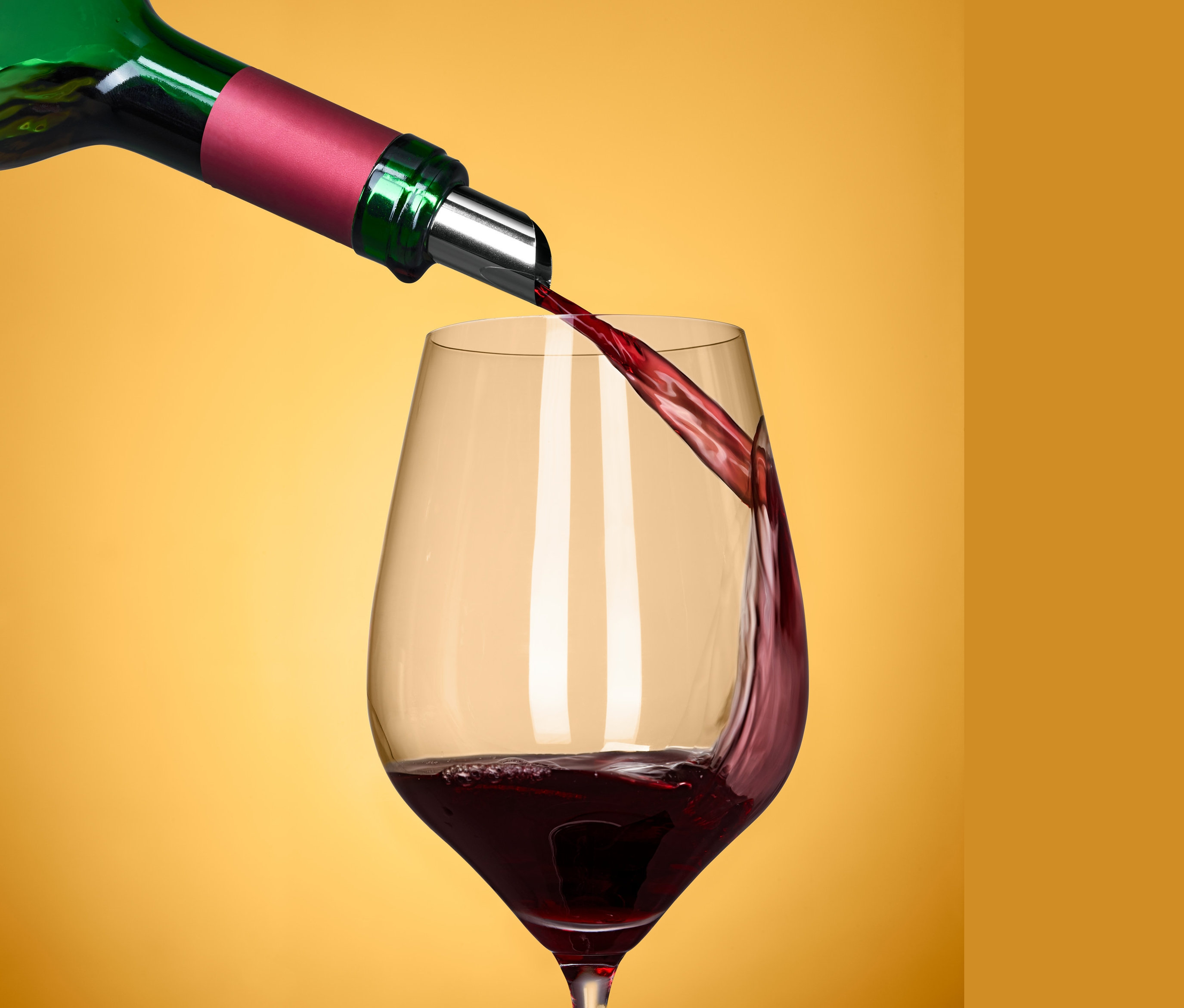 Grüne Flasche mit 2 DropStop® giesst Rotwein in ein Weinglas.