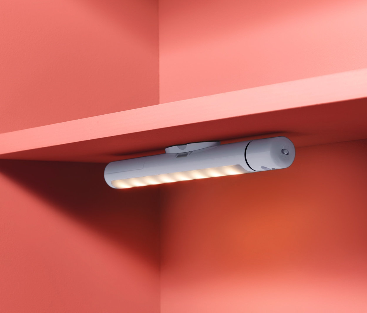 Eine LED-Multifunktionsleuchte ist an der Unterseite eines Regals befestigt und beleuchtet den Bereich.