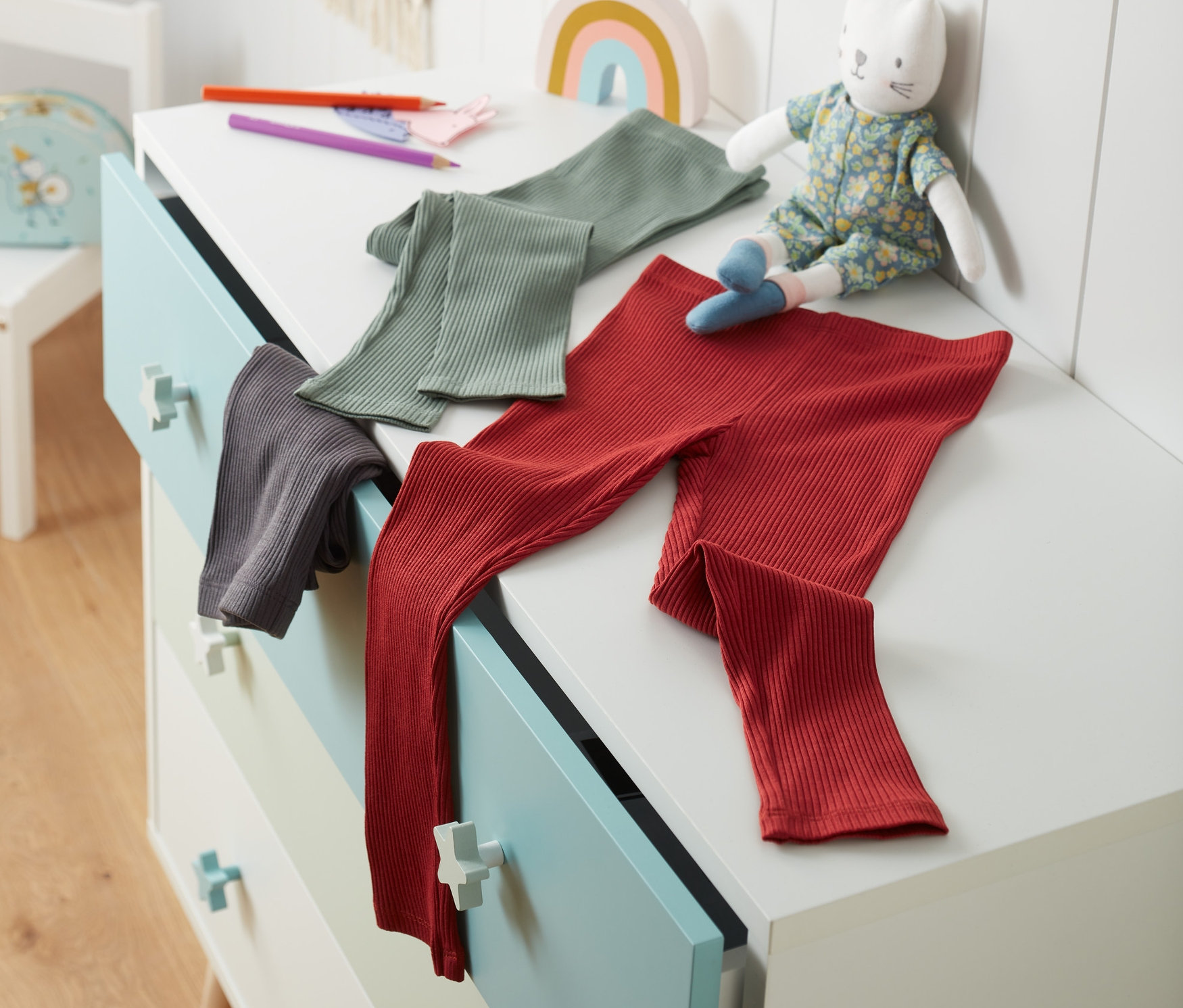 Drei Leggings aus Bio-Baumwolle liegen auf einer Kommode.