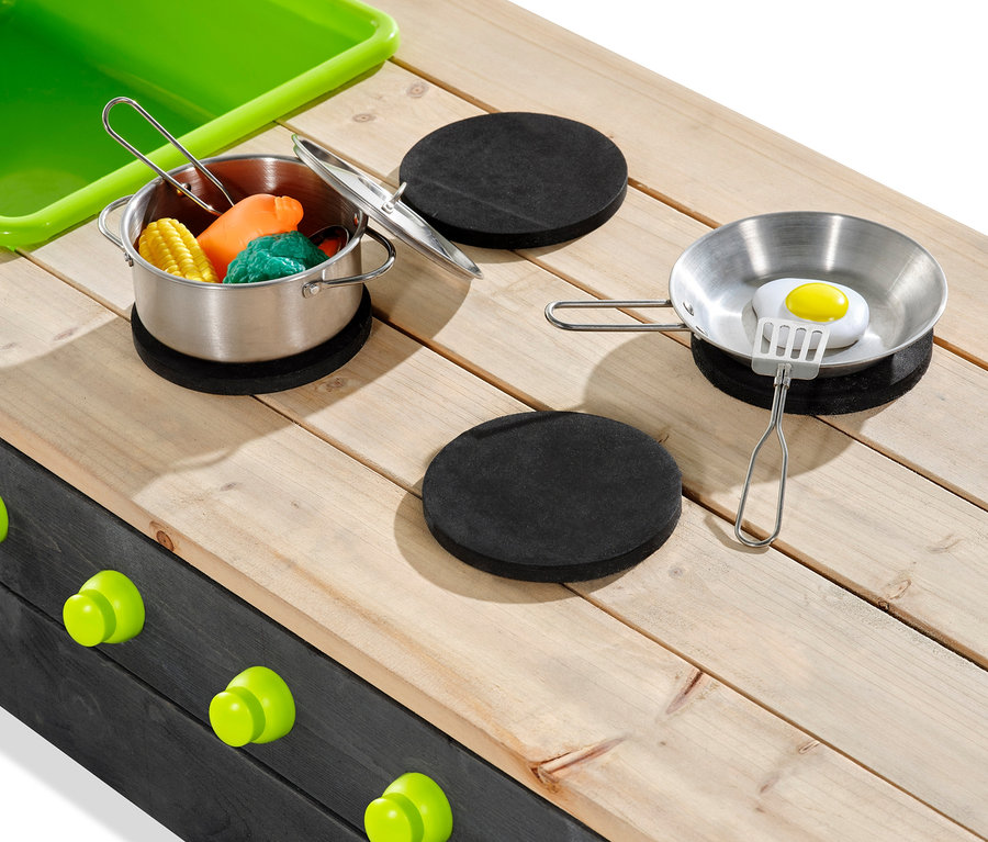 Ein Topf mit Mais und Gemüse und eine Pfanne mit Ei auf einem Holztisch, im Hintergrund der EXIT Holz-Sandkasten »Aksent«, ca. 200 x 140 cm.