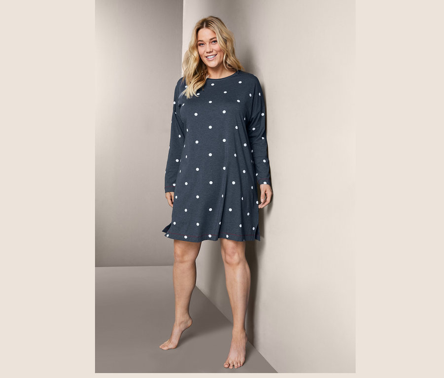 Frau steht und trägt ein Nachthemd mit Punkten.
