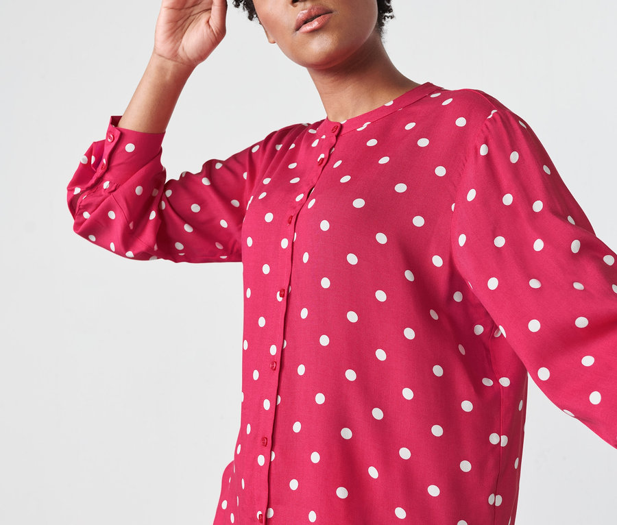 Frau posiert in gepunkteter Webbluse.