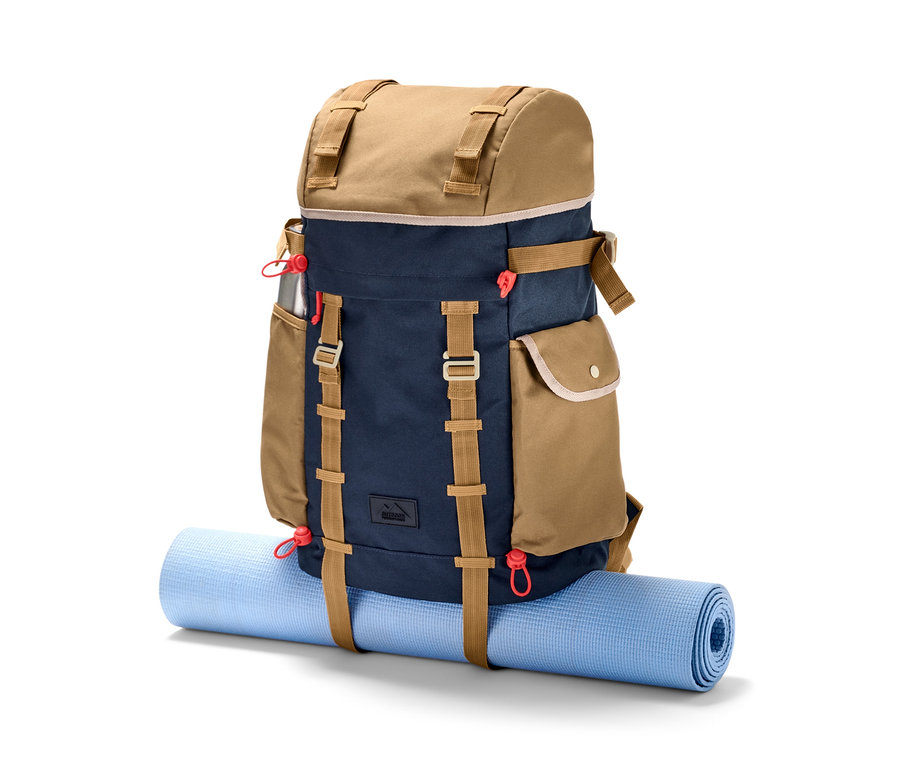 Ein braun-blauer Outdoor-Rucksack liegt auf einer zusammengerollten blauen Matte.