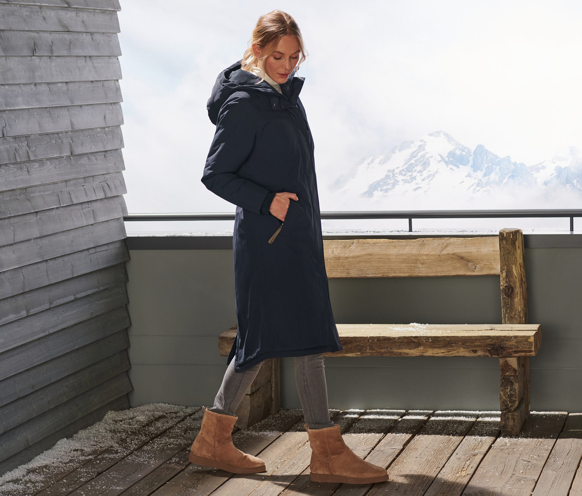 Frau geht, sie trägt einen extralangen Thermomantel.