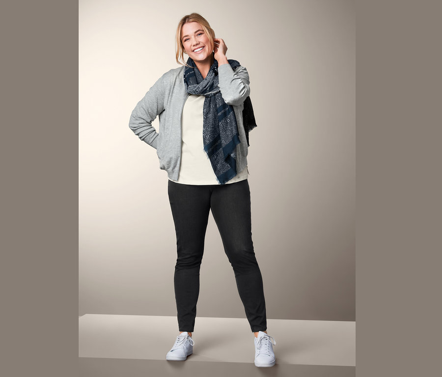 Frau posiert in Jeggings, Strickjacke, Webschal und Shirt mit 3/4-Arm.