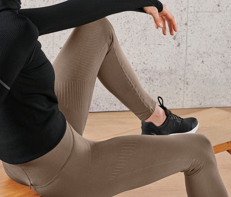 Frau sitzt auf Bank, trägt Premium-Seamless-Lauftight und schwarze Sneaker.