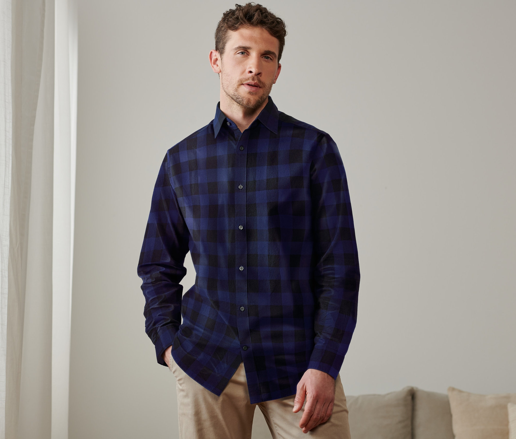 Ein Mann posiert in einem blau karierten Flanellhemd.
