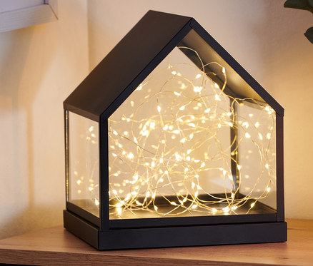 Auf einer Holzkommode steht ein LED-Glashäuschen.