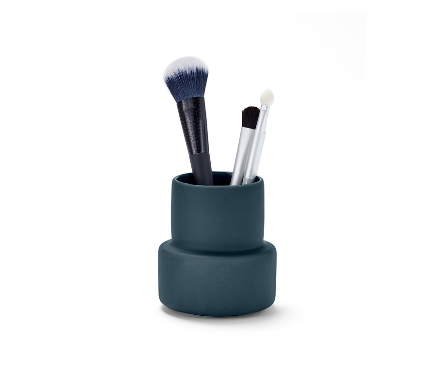 Drei Make-up-Pinsel stehen in einem blauen Utensilo.