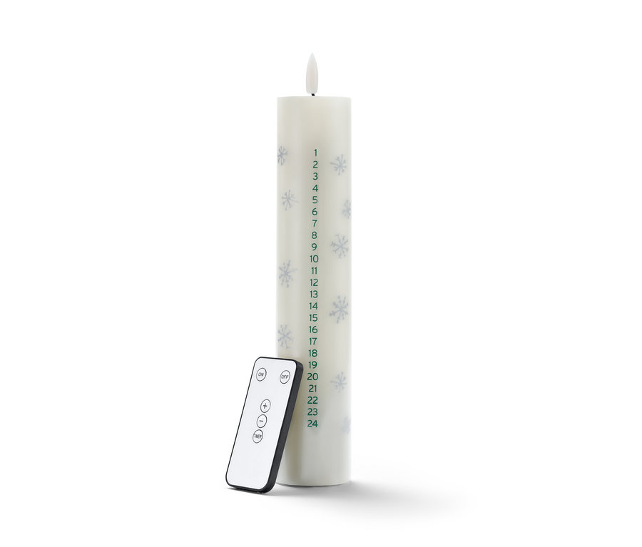 Eine LED-Echtwachs-Adventskalenderkerze mit Fernbedienung steht auf einem weißen Untergrund.