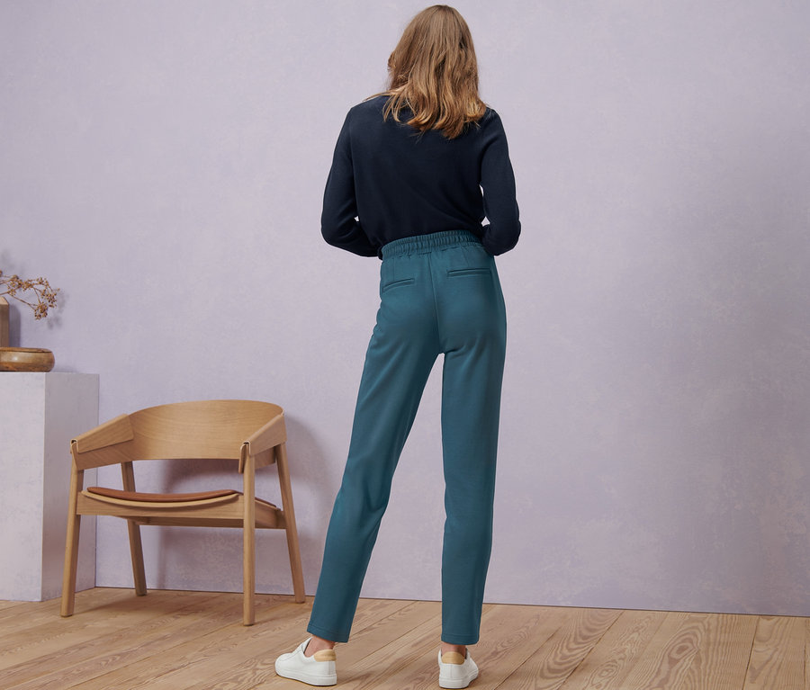Frau steht mit dem Rücken zur Kamera und trägt eine Joggpants.