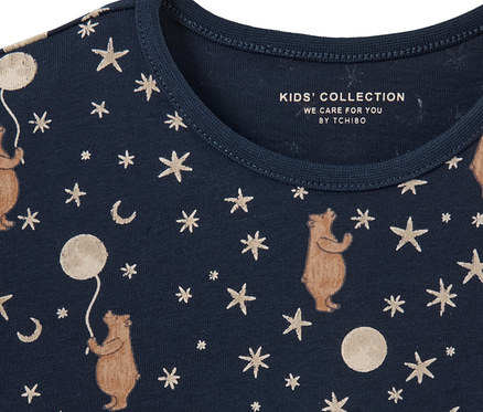 Detailansicht eines Kinder-Pyjamas mit Bären-, Stern- und Mond-Print auf dunkelblauem Hintergrund.