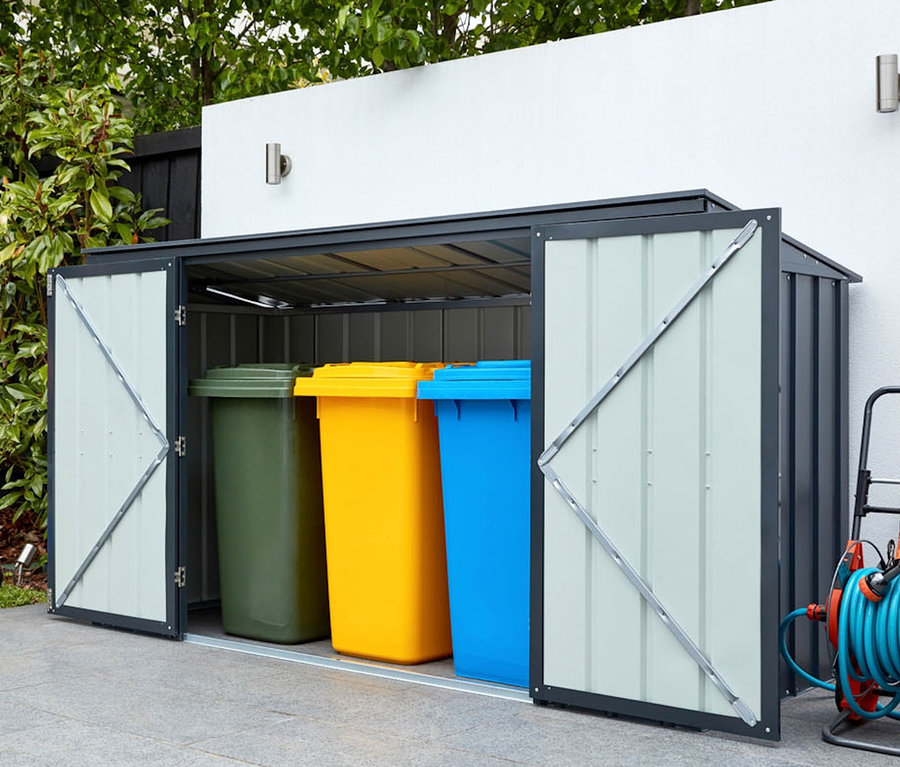 Geöffneter Gerätebox mit bunten Mülltonnen, daneben Rasenmäher und Schlauchaufroller.