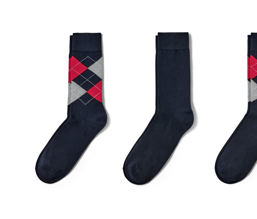 Drei blaue Socken liegen nebeneinander. Zwei davon haben ein Rautenmuster.