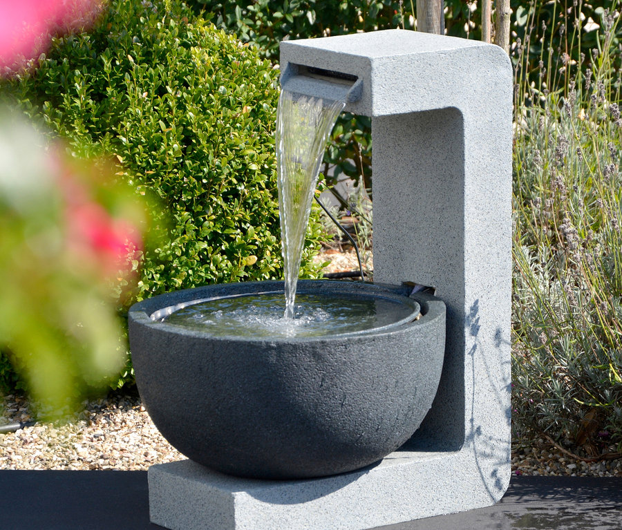 Grauer Dobar Gartenbrunnen mit Schale und fließendem Wasser in einem Garten.