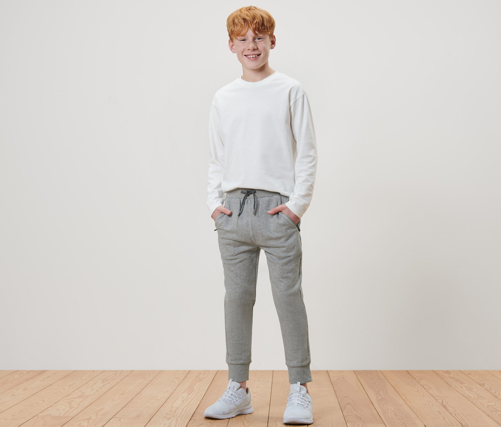 Junge steht mit Händen in den Taschen einer Kinder-Sweathose.