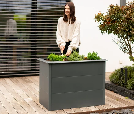 Frau arbeitet in einem 100 cm Hochbeet mit Schneckenschutz.