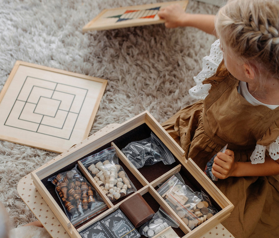 Kinder sitzen auf einem Teppich und spielen small foot Spielesammlung, 20 Klassiker.